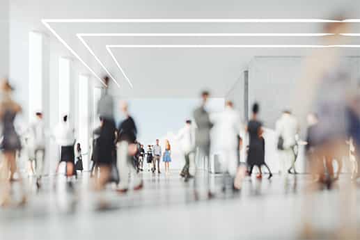 a miz of pedestrians walking through a crowded office lobby